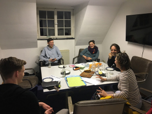 Eine Gruppe junger Menschen sitzt an einem Tisch und diskutiert