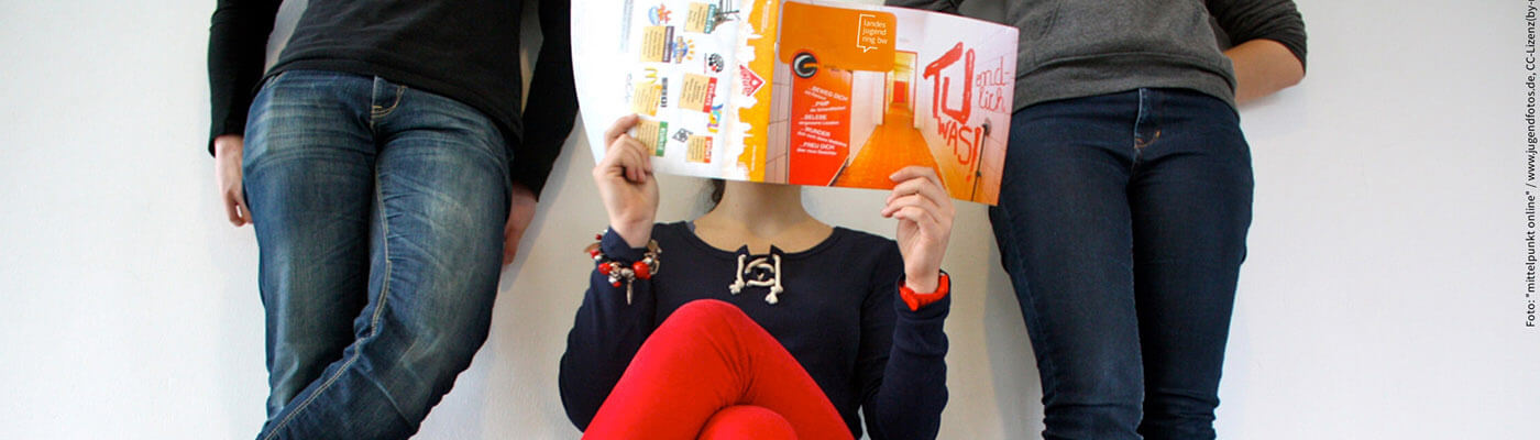 drei Personen lesen einer Zeitung