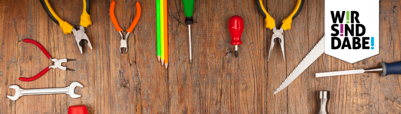 Auf dem Bild sind verschiedene bunte Werkzeuge auf einer Holzwerkbank zu sehen.