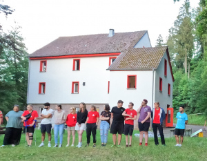 Jugendliche stehen auf einer Wiese in einer Reihe und spielen ein Spiel